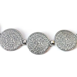 Pode incluir: Pulseira de prata com pingentes circulares que apresentam desenhos e padr&otilde;es intrincados. Cada pingente tem uma inscri&ccedil;&atilde;o circular de texto.