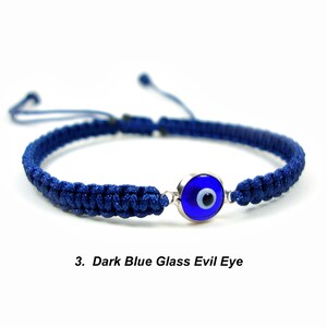May include: A dark blue braided bracelet with a dark blue glass evil eye charm. The charm has a white center and a silver rim.