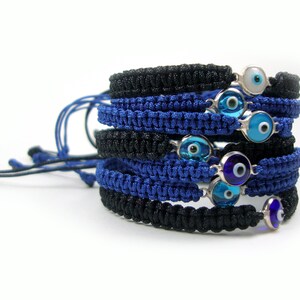 May include: A stack of blue and black braided bracelets with silver charms featuring blue evil eyes.