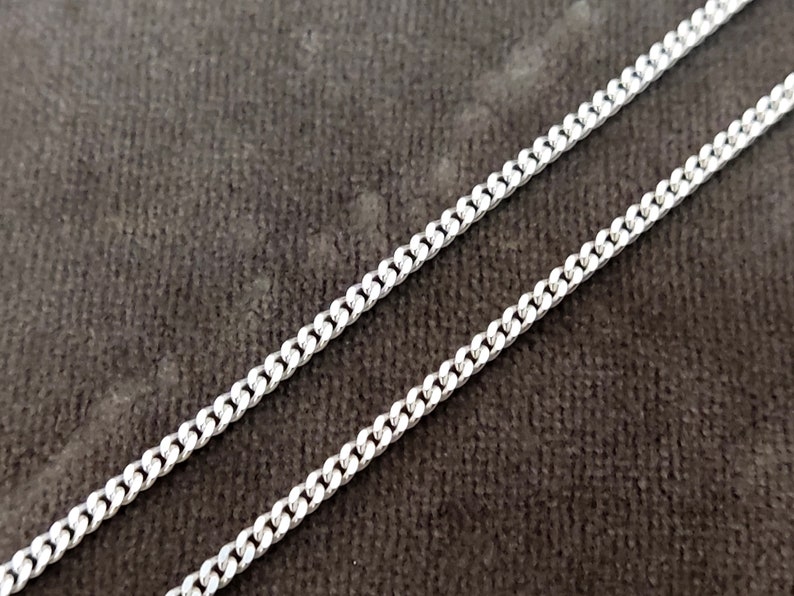 K&ouml;nnte beinhalten: Eine silberne Curb-Kette. Die Kette besteht aus kleinen, ineinandergreifenden Gliedern.
