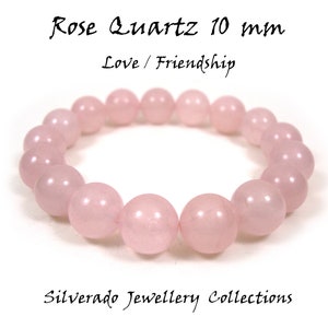 Può includere: Un braccialetto in quarzo rosa da 10 mm. Il braccialetto è realizzato con pietre naturali ed è progettato per promuovere l'amore e l'amicizia. "Rose Quartz 10 mm Love / Friendship" è scritto sullo sfondo bianco.