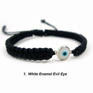 May include: Black braided bracelet with a white enamel evil eye charm. The charm has a blue center.