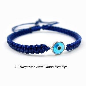 May include: A blue braided bracelet with a turquoise blue glass evil eye charm. The charm has a silver rim.