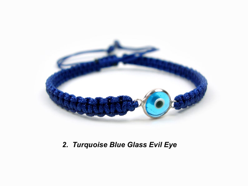 May include: A blue braided bracelet with a turquoise blue glass evil eye charm. The charm has a silver rim.