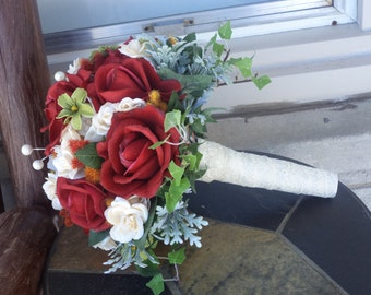 May include: A bridal bouquet featuring red roses, white flowers, and green foliage.