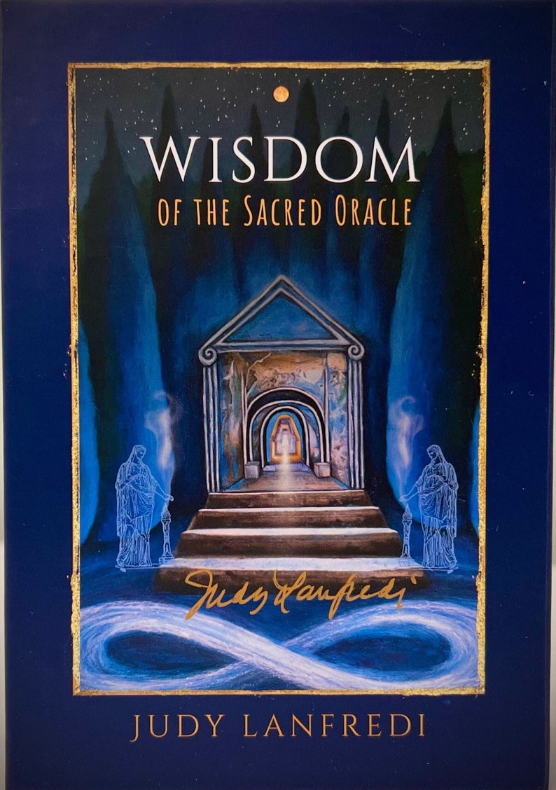 May include: A navy blue oracle card deck titled "Wisdom of the Sacred Oracle" with gold accents. The cover art features a detailed illustration of a temple entrance, with figures holding torches, and the artist's signature.