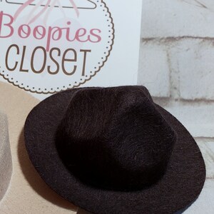 May include: A black felt fedora hat with a wide brim. The hat has a slightly pointed crown.