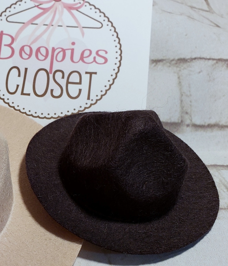 May include: A black felt fedora hat with a wide brim. The hat has a slightly pointed crown.