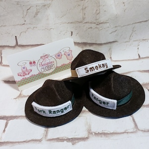 May include: Three brown felt ranger hats with green trim and white embroidered patches. The patches read "Smokey", "Park Ranger", and "Ranger".