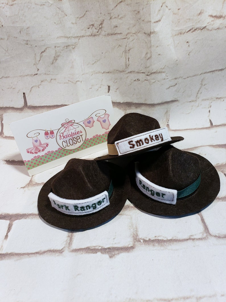 May include: Three brown felt ranger hats with green trim and white embroidered patches. The patches read "Smokey", "Park Ranger", and "Ranger".