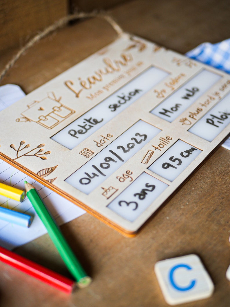 May include: A wooden sign with a white background and black text. The sign is labeled "Mon premier jour" and has sections for "Petite section", "Date", "Age", "Taille", "Mon velo", "Plus tard je serai", and "Pilo". The date is filled in as "04/09/2023", the age is filled in as "3 ans", and the height is filled in as "95 cm".