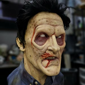 Puede incluir: Primer plano de una máscara de zombi realista con un aspecto detallado y horrible. La máscara presenta una tez pálida, rayas rojo sangre y una boca abierta con dientes visibles. La máscara está hecha de un material de alta calidad y es perfecta para Halloween o cosplay.