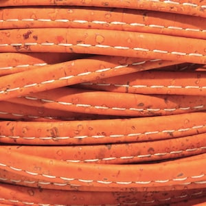 Puede incluir: Primer plano de un cordón de cuero de corcho naranja con costuras blancas. El cordón está enrollado y las costuras son visibles en cada lazo.