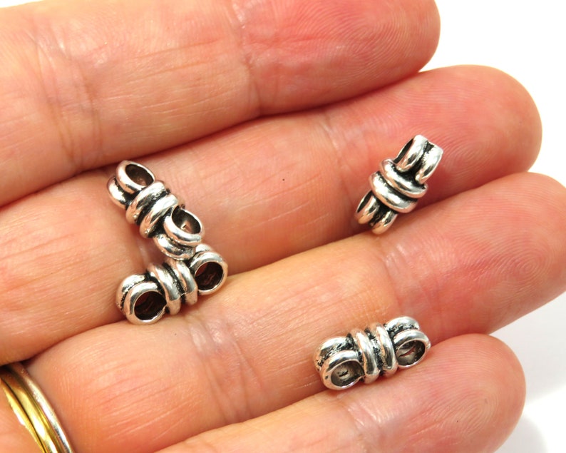 K&ouml;nnte beinhalten: Drei silberne Metallperlenkappen mit einem Knotendesign. Die Perlenkappen sind so konzipiert, dass sie als Endkappen f&uuml;r Halsketten, Armb&auml;nder oder anderen Schmuck verwendet werden k&ouml;nnen.