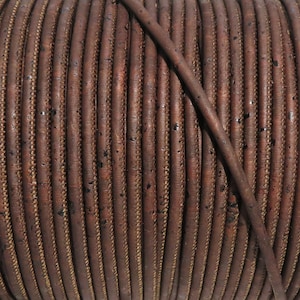 May include: A close-up of a spool of brown cork cord. The cord is tightly wound and has a slightly textured surface.
