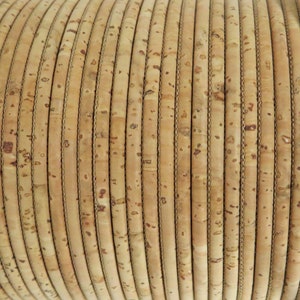 May include: Close-up of a roll of natural cork cord, a textured material with a light brown color. The cord is wound tightly in a spiral shape.