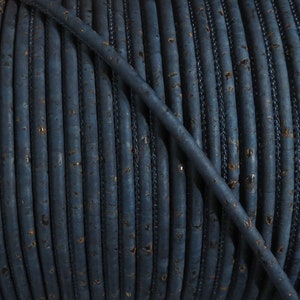 Puede incluir: Primer plano de un carrete de cordón de corcho azul oscuro. El cordón está hecho de corcho natural y tiene una superficie ligeramente texturizada.