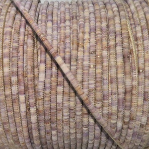 May include: A close-up of a spool of light purple and beige cord. The cord is made of small, flat, round pieces of leather that are sewn together.