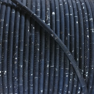 Puede incluir: Primer plano de una bobina de cable azul oscuro enrollada. El cable tiene una superficie texturizada con motas plateadas y una costura cosida. El cable probablemente se utiliza para manualidades o fines decorativos.