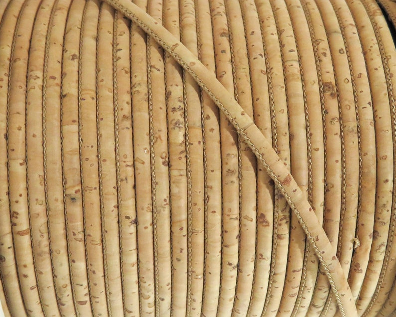 May include: Close-up of a spool of natural cork cord, a type of leather cord with a textured surface.
