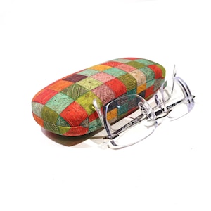 Pode incluir: Óculos com armação transparente e estojo para óculos com design patchwork. O estojo oval apresenta um design patchwork em tons de vermelho, verde, laranja e amarelo. O estojo tem cerca de 17 cm de comprimento.