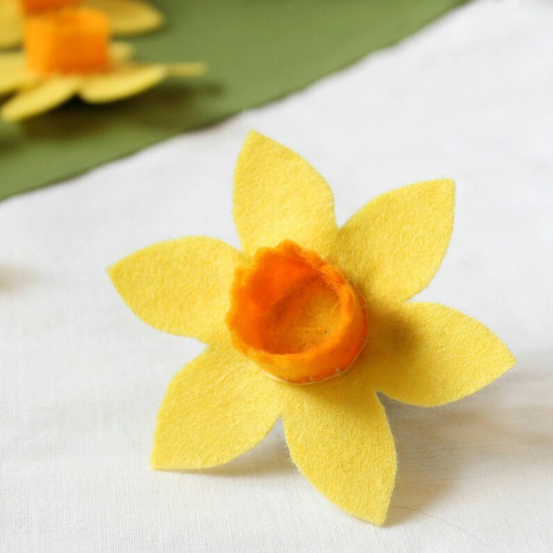 A yellow felt daffodil with an orange felt centre The flower has six petals and is a dog collar decoration.