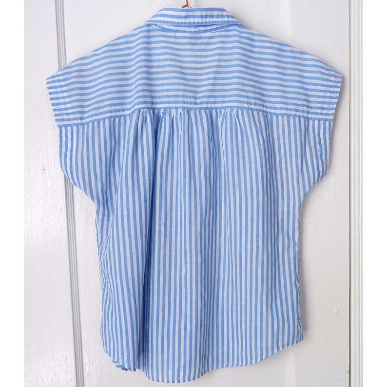 May include: A blue and white striped short-sleeved button-up shirt with a gathered back.