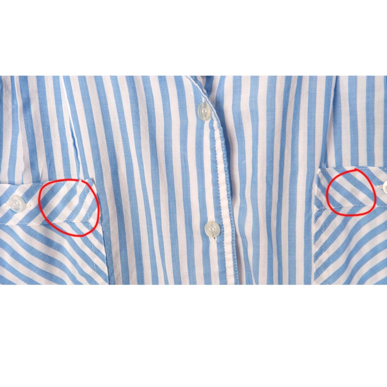 May include: A blue and white striped shirt with a button-up front and two pockets. The shirt has a diagonal stripe pattern on the pockets.