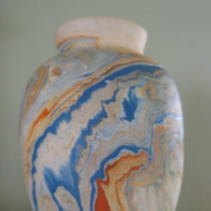 May include: A white ceramic vase with a marbled design in shades of blue, orange, and brown.