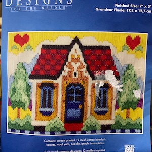 以下が含まれることがあります： 赤と白のチェック柄の家が青いドアと黄色い窓で描かれたクロスステッチのパターンです。家は緑の木々と黄色の空に囲まれています。パターンは「No Place Like Home」というタイトルで、Designs for the Needleブランドです。完成サイズは17.8cm x 12.7cmです。