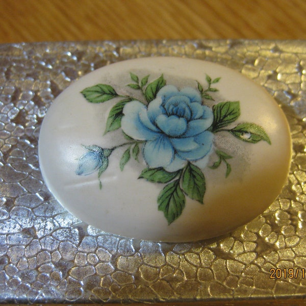 Oval, fired ceramic clay, off white with blue flower decoupaged design, brooch, pin.  Rolled Pin clasp back; hand made; hand painted