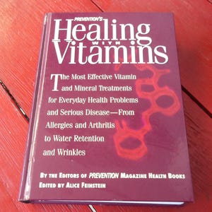 May include: A hardcover book titled "Healing with Vitamins" by the Editors of Prevention Magazine Health Books. The cover is a deep burgundy color with white text and a red graphic. The book's subtitle discusses vitamin and mineral treatments.