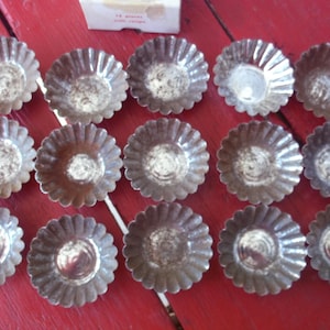 May include: A white ceramic mug with a black handle and the text "But First, Coffee" in a bold, black font. The mug is set against a blurred background, suggesting a cozy setting.