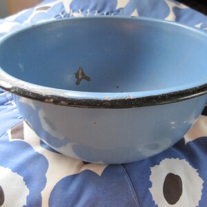 May include: A light blue enamel bowl with a black rim. The bowl is slightly chipped on the rim.