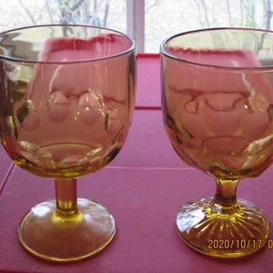 May include: Two amber glass goblets with a textured design. The goblets have a round bowl and a short stem with a flared base.