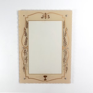 Może przedstawiać: Lustro ze szkła w kolorze kremowym z ozdobną ramą. Rama zdobiona jest złotym wzorem z kłosami pszenicy, winogronami i literami "JHS".