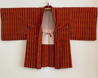 May include: A red and green plaid Japanese kimono with a long sleeve design. The kimono is open in the front and has a white lining.