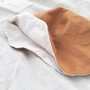 May include: A brown and white bucket hat made of fabric. The hat is folded in half and the brown side is facing up.