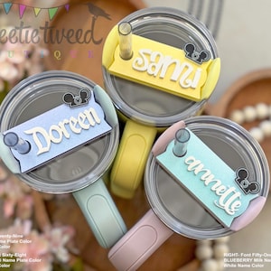 May include: Three personalized tumbler lids with names: "Sami", "Doreen", and "Annette". Each lid has a different pastel color and a Mickey Mouse silhouette. The names are in white, stylized fonts. The tumblers have straws and handles.