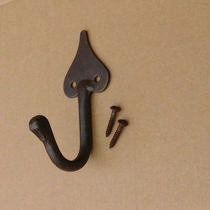 Może przedstawiać: Rustykalny czarny metalowy hak z ostrym wierzchołkiem i zakrzywionym hakiem. Dołączono dwie śruby do montażu.