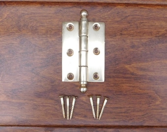 May include: A silver-toned door hinge with a rounded knob on the top and bottom. The hinge is accompanied by eight small screws.