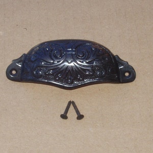 May include: Black metal drawer pull with an ornate design. The pull comes with two screws.