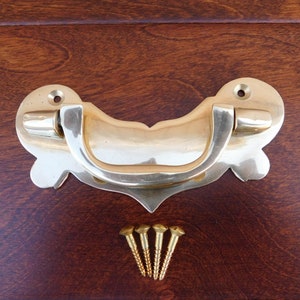 以下が含まれることがあります： 装飾的なデザインの真鍮製のドアプル。プルは木製の表面に取り付けられており、4本のネジが付属しています。