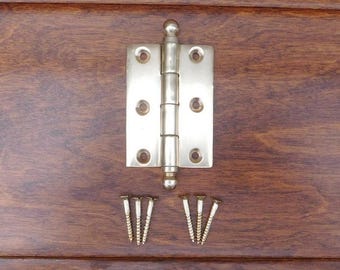 May include: A silver-toned door hinge with a rounded top and four screws. The hinge is on a wooden surface.