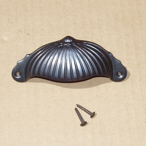 May include: Black metal cabinet pull with a shell-like design and two screws.