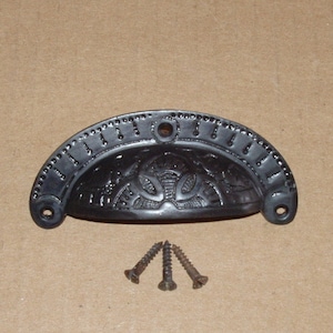 May include: Black metal drawer pull with an ornate design and three screws.