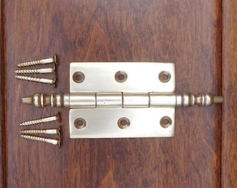 May include: A silver-toned door hinge with a decorative finial on each end. The hinge is shown with screws.