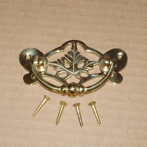 May include: Brass cabinet pull with a leaf design and a curved handle. The pull comes with four screws.
