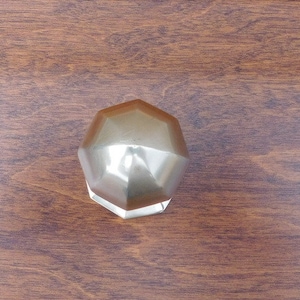 May include: A silver-coloured, geometric, dodecahedron-shaped object with a smooth, reflective surface.