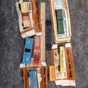 Puede incluir: Una colección de vagones de tren de juguete y accesorios antiguos, que incluyen vagones cubiertos, vagones planos y piezas de vías. Los vagones son de varios colores, como azul, rojo y verde, y están empaquetados en sus cajas originales. Algunas cajas tienen las marcas "TYCO" y "Life-Like".
